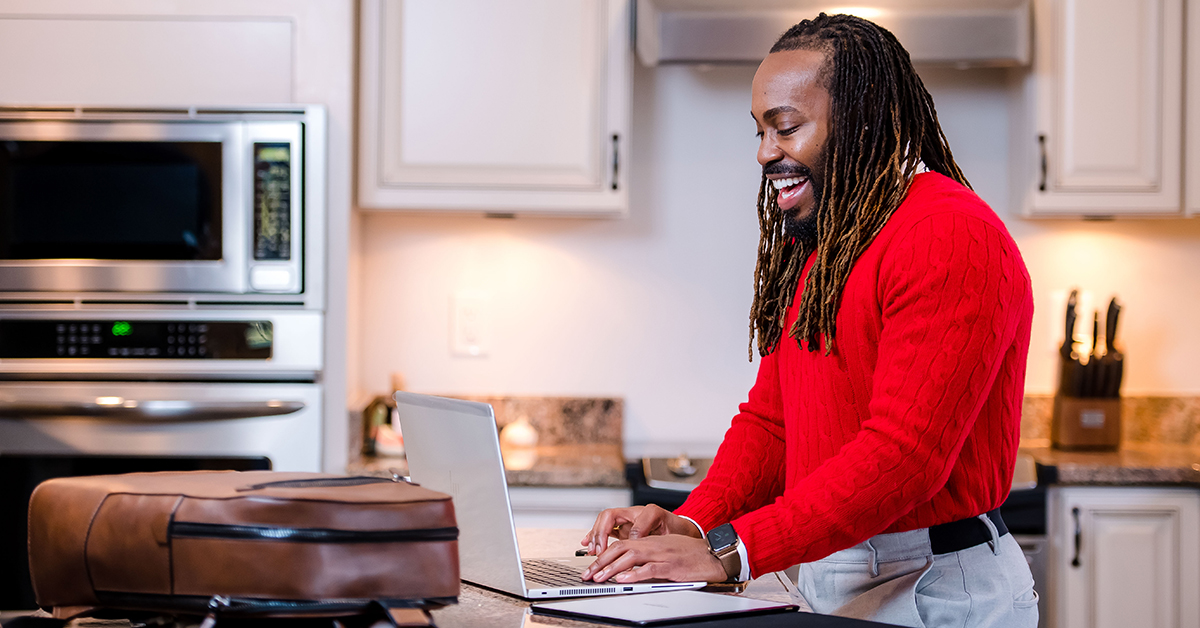 Todd, Capital One associate, stands in his kitchen at his laptop while working from home. He appreciates that Capital One has prioritized his wellbeing while working at home. 